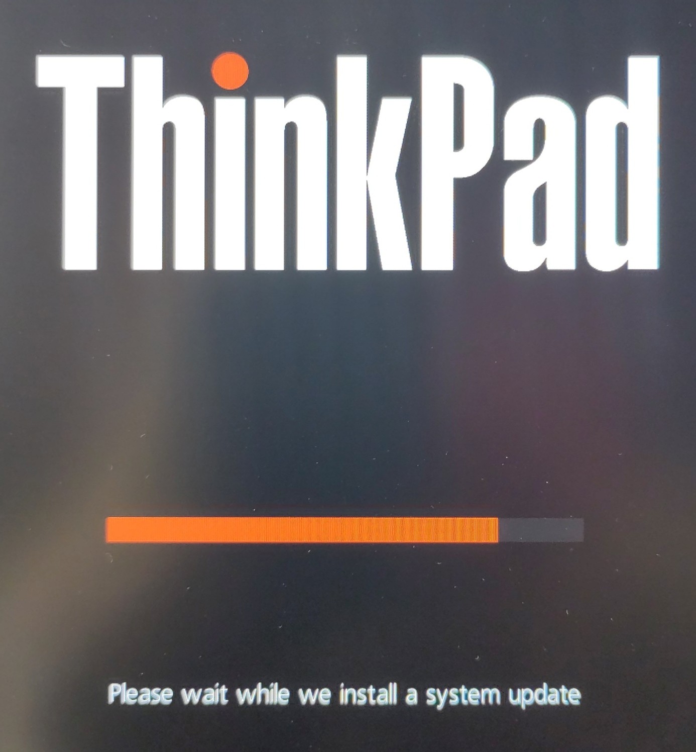 A photo of my ThinkPads screen showing the ThinkPad logo and a red progress bar with the text underneath. "Please wait whilst we install a system update"