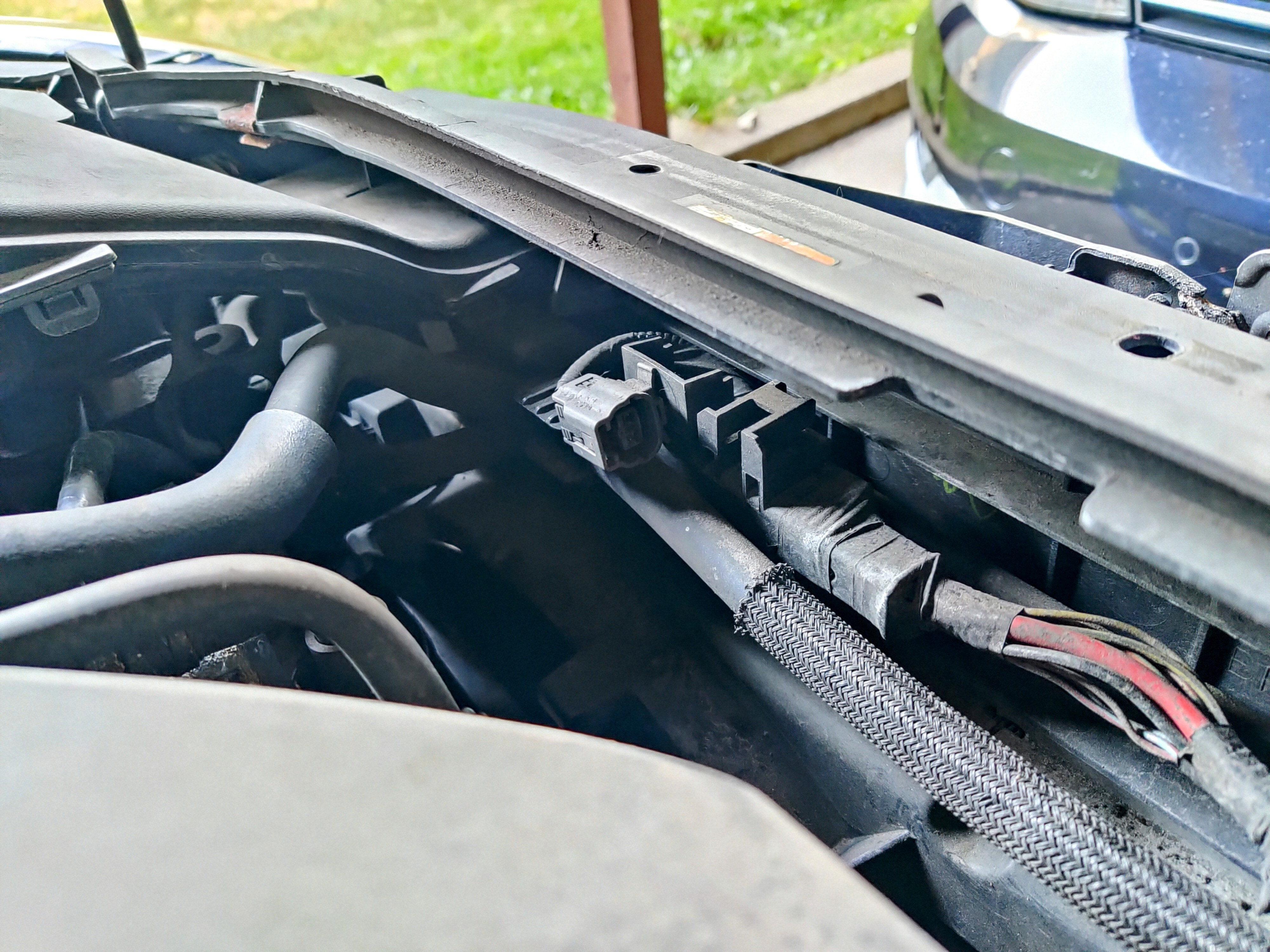 A view under the hood of a 2007 Mazda 3 from the right (passenger) side showing an unused electrical connector near the top front of my engine compartment next to the battery box fresh air intake.